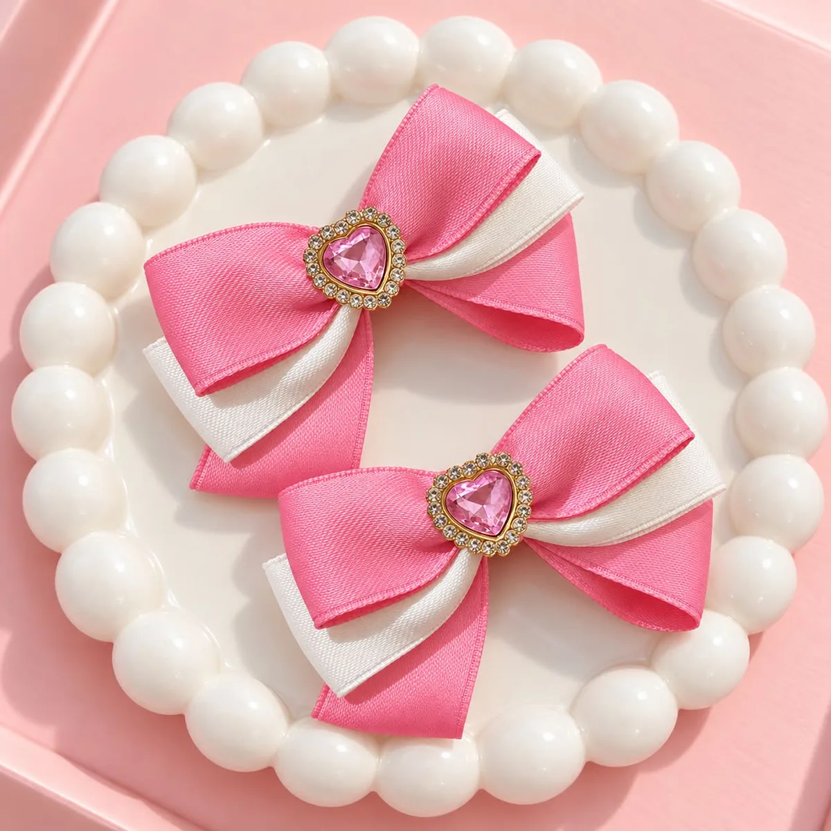 Pink Luxe Bow Pair: Layered pink and ivory ribbon bows with a pink heart-shaped jeweled centerpiece.